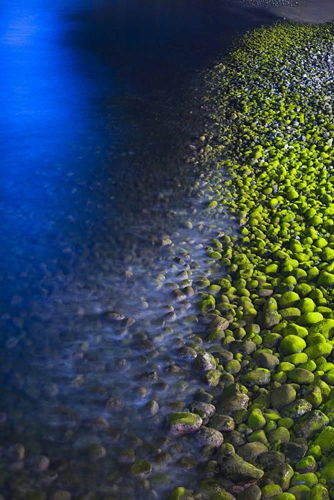 Algae covered pebbles on the beach at night, Ponta do Sol, Madeira, Portugal