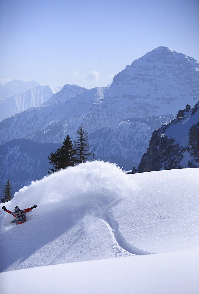 Snowboarder carving turns downhill, Reutte, Tyrol, Austria