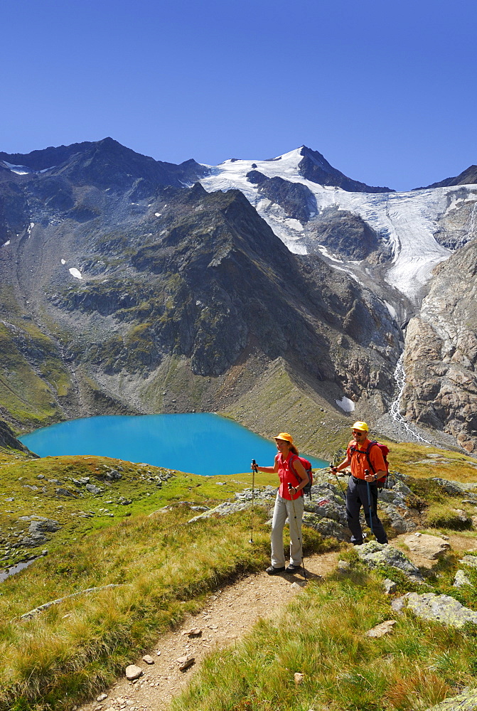 couple hiking above lake Gruenausee, Wilder Freiger and galcier Wiilder-Freiger-Ferner in background, Stubaier Alpen range, Stubai, Tyrol, Austria