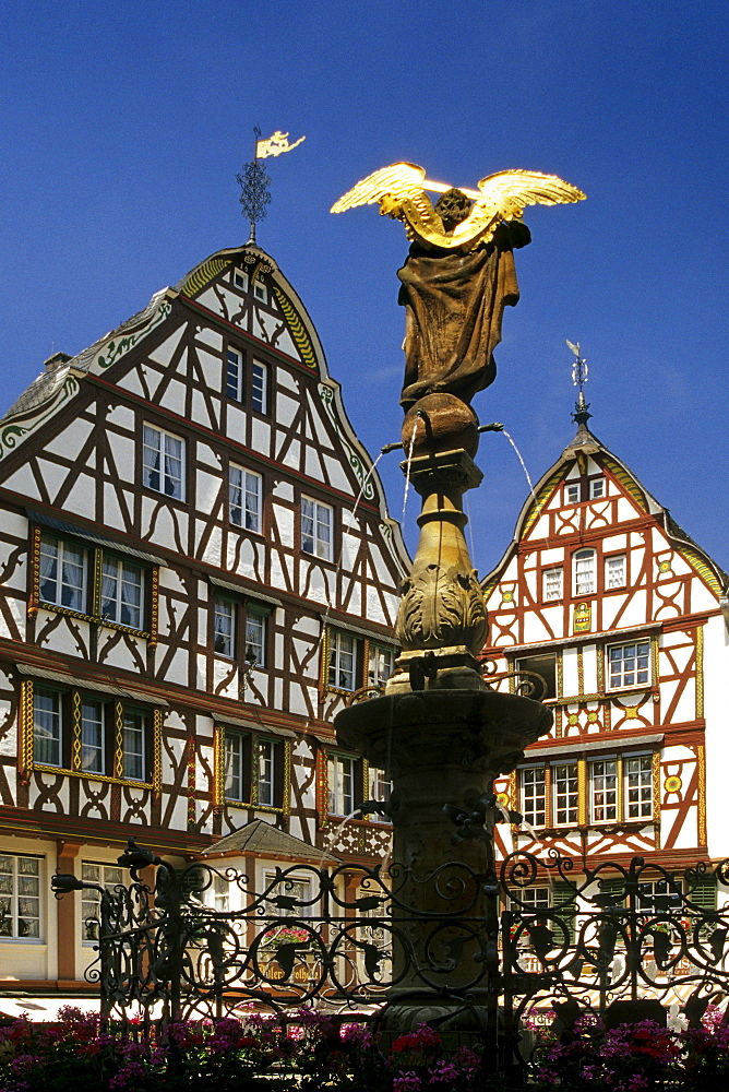 Sculpture on a fountain and half-timbered houses under blue sky, Bernkastel-Kues, Rhineland-Palatinate, Germany