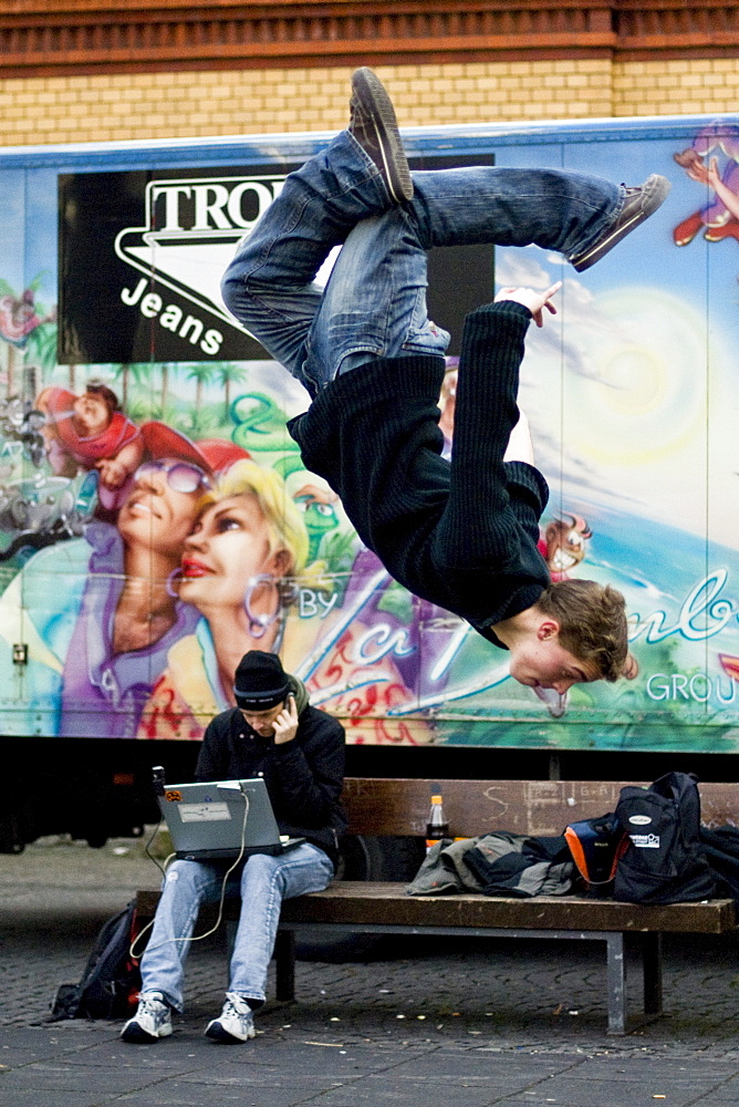 Teenager performing a somersault, Young man sitting with his laptop, Leisure, Ingolstadt, Bavaria, Germany