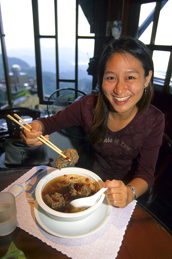 Laughing woman eating at a restaurant at Chiufen, Taiwan, Asia