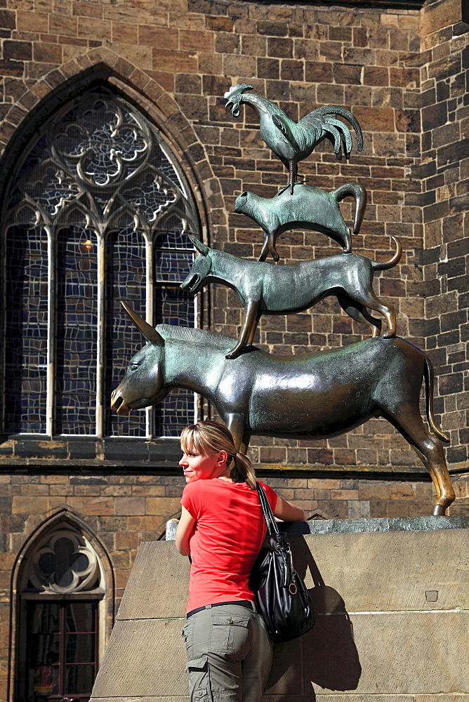 Young woman posing in front of the Bremen town musicans, Hanseatic City of Bremen, Germany, Europe