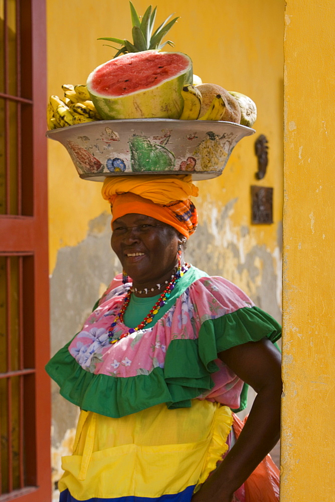 Woman in colorful costume with bowl of fruit on head, Cartagena, Bolivar, Colombia