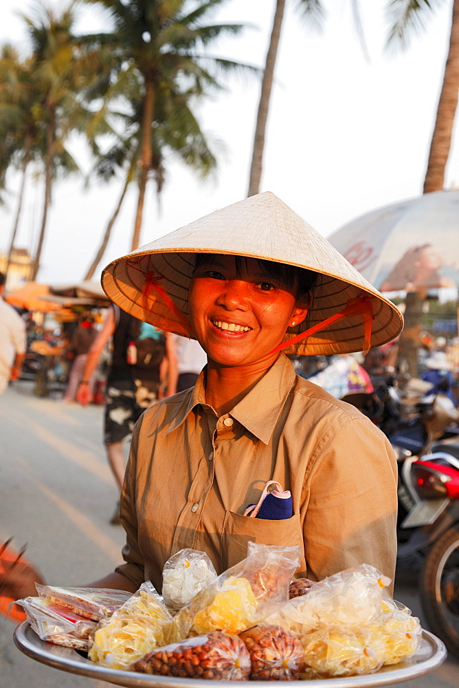 Woman offering sweets in harbor, Hoi An, Annam, Vietnam