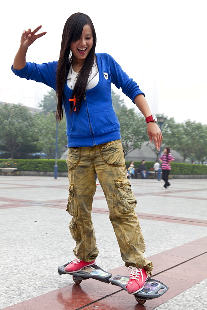 Chinese girl riding a special skateboard, leisure time, public square in front of the Walmart Shopping centre, Shapingba District, Chongqing, People's Republic of China