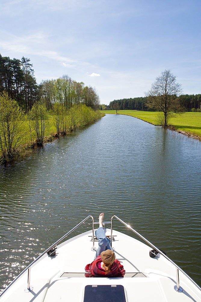 Woman relaxing on the bow of a houseboat near Zechlinerhuette, North Brandenburg Lake District, Brandenburg, Germany