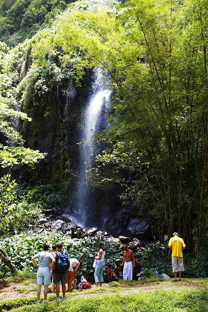 People in front of a waterfall at Anse des Cascade in Bois-Blanc, La Reunion, Indian Ocean