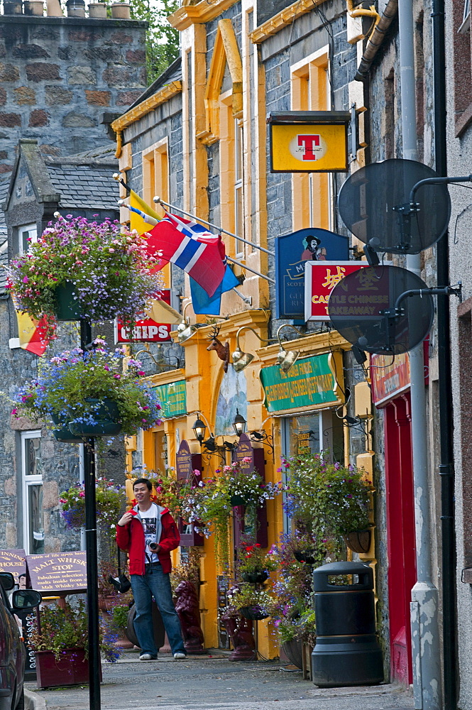 Tourist in front of a pub in Dufftown, Aberdeenshire, Scotland