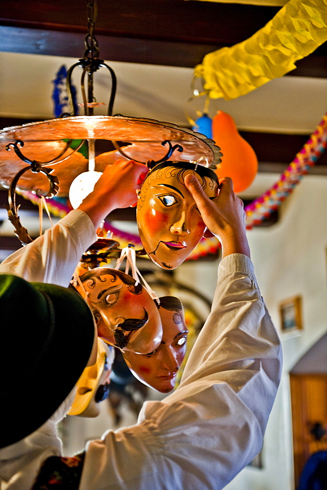 Disguised person hanging masks on a lamp, Mittenwald, Bavaria, Germany, Europe