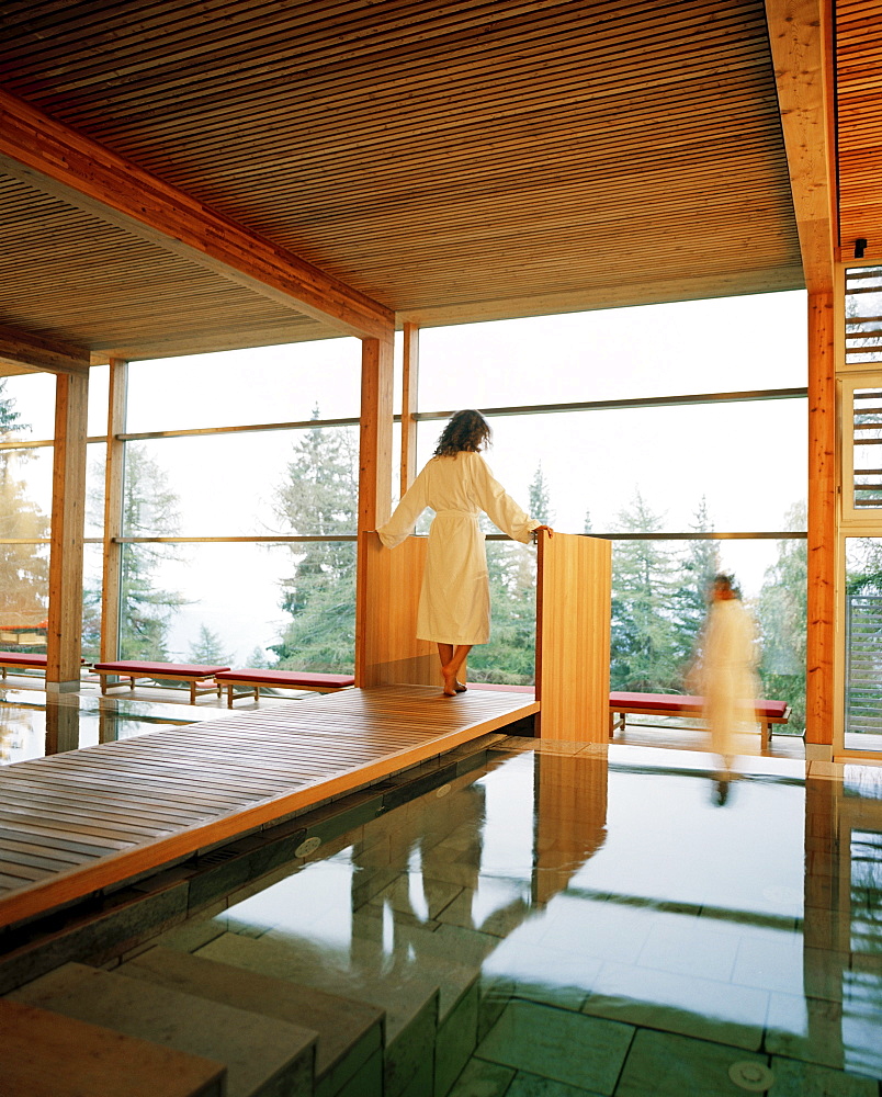 Couple near indoor pool looking out of a panorama window, Vigilius Mountain Resort, Vigiljoch, Lana, Trentino-Alto Adige/Suedtirol, Italy