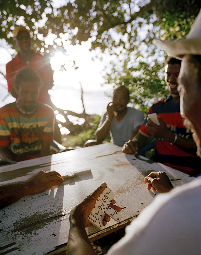 Men playing domino on the beach in the evening, La Passe, La Digue, La Digue and Inner Islands, Republic of Seychelles, Indian Ocean