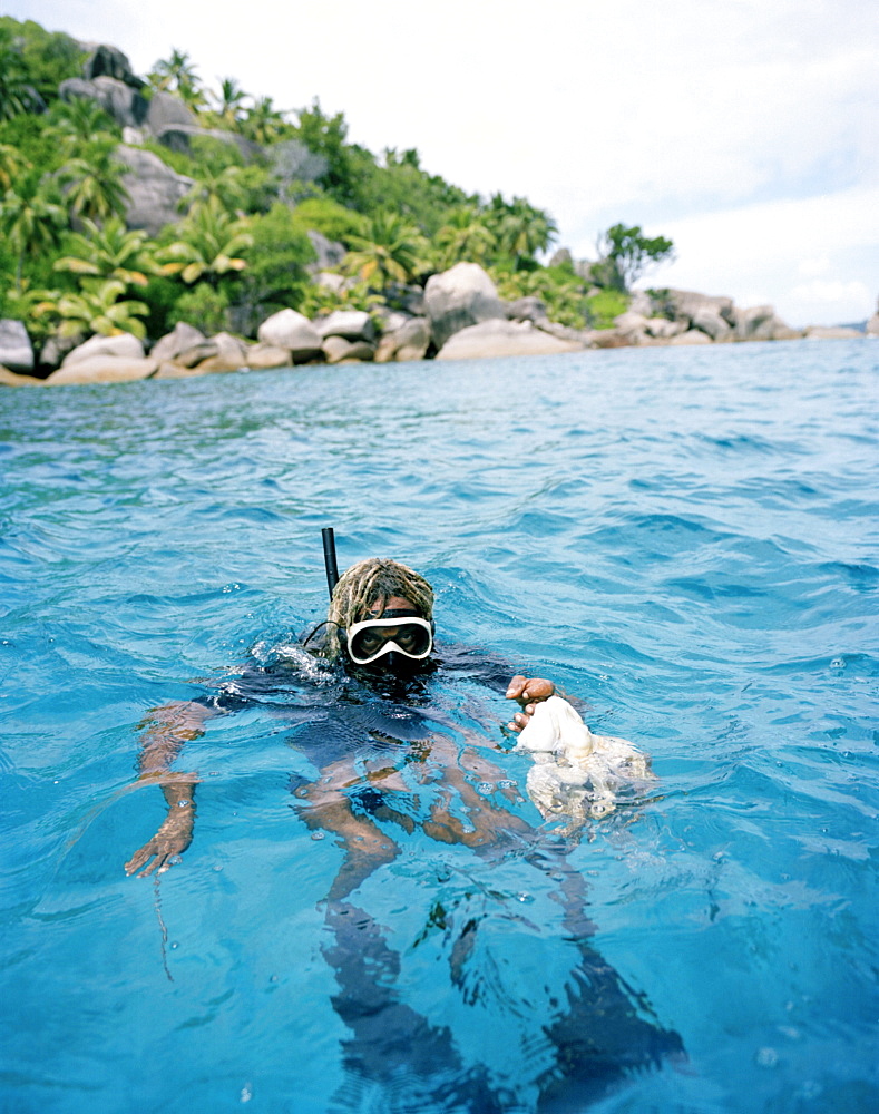 Octopus hunter Alvis Jean snorkeling off FelicitÃˆ island with squid, Coleoidea, La Digue and Inner Islands, Republic of Seychelles, Indian Ocean