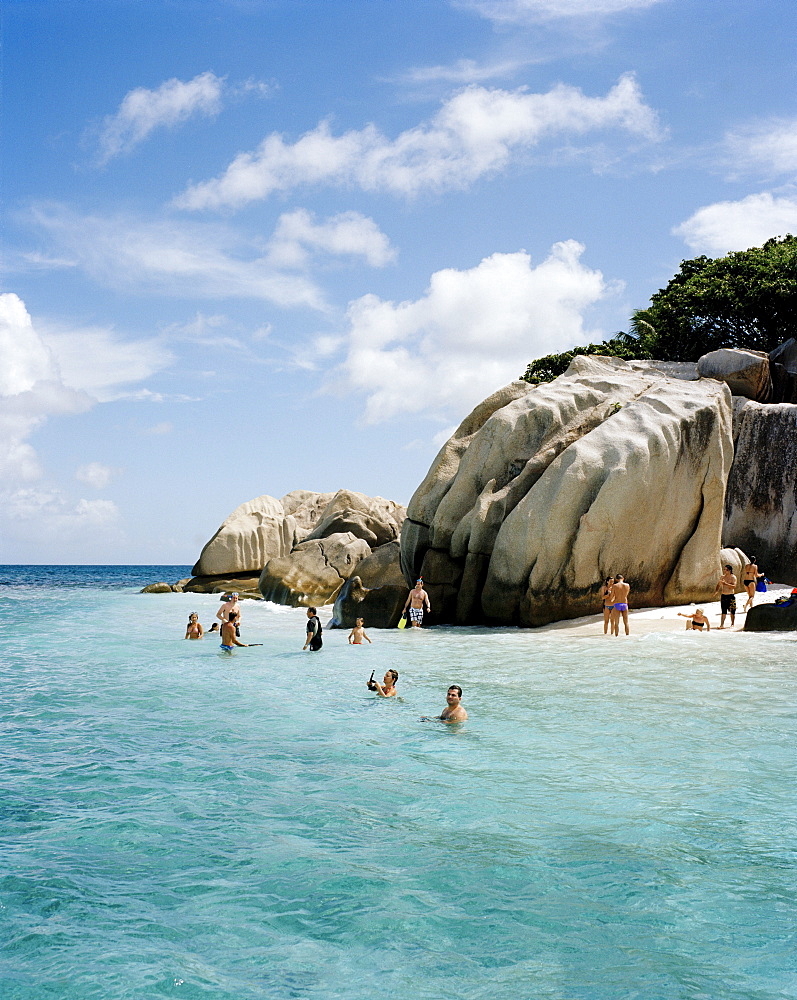 People snorkelling in shallow water over coral reef off tiny Coco Island, La Digue and Inner Islands, Republic of Seychelles, Indian Ocean