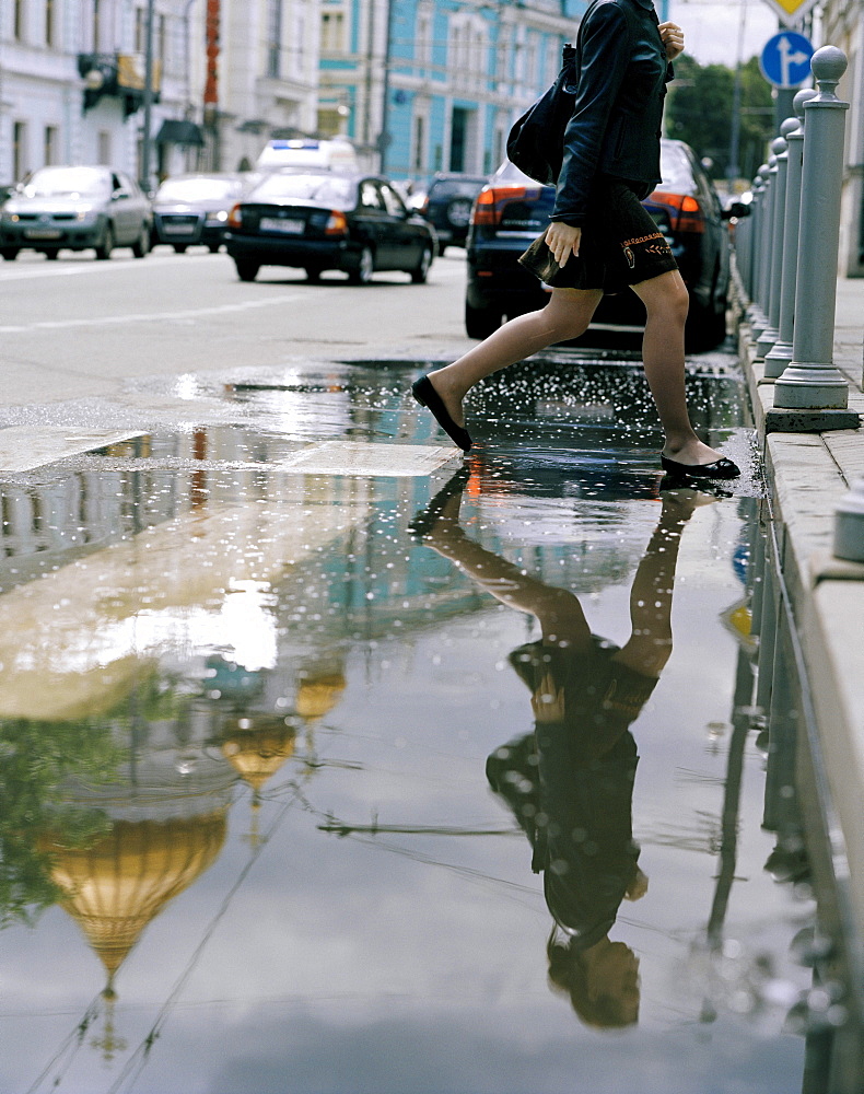 Pedestrian crossing a puddle in Wolchonka Uliza street, Moscow, Russia, Europe