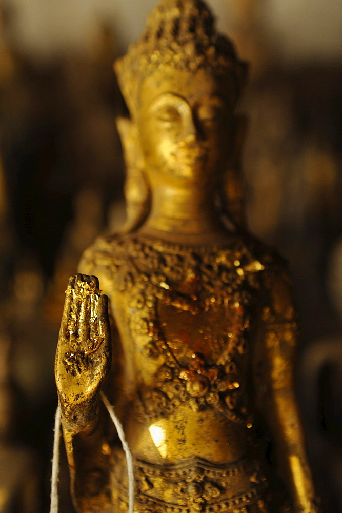 Buddha with raised hand in the mudra of beeing fearless, Buddha statues, Pak Ou caves, Mekong river north of Luang Prabang, Laos