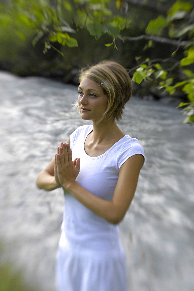 Young woman doing yoga at the banks of a river, Alto Adige, South Tyrol, Italy, Europe