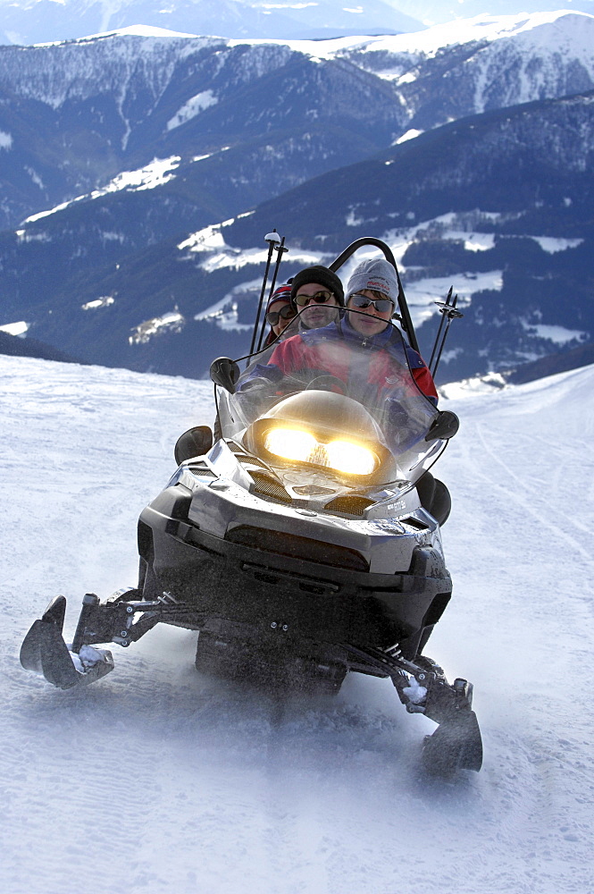 Three people on a snowmobile in the mountains, Alto Adige, South Tyrol, Italy, Europe