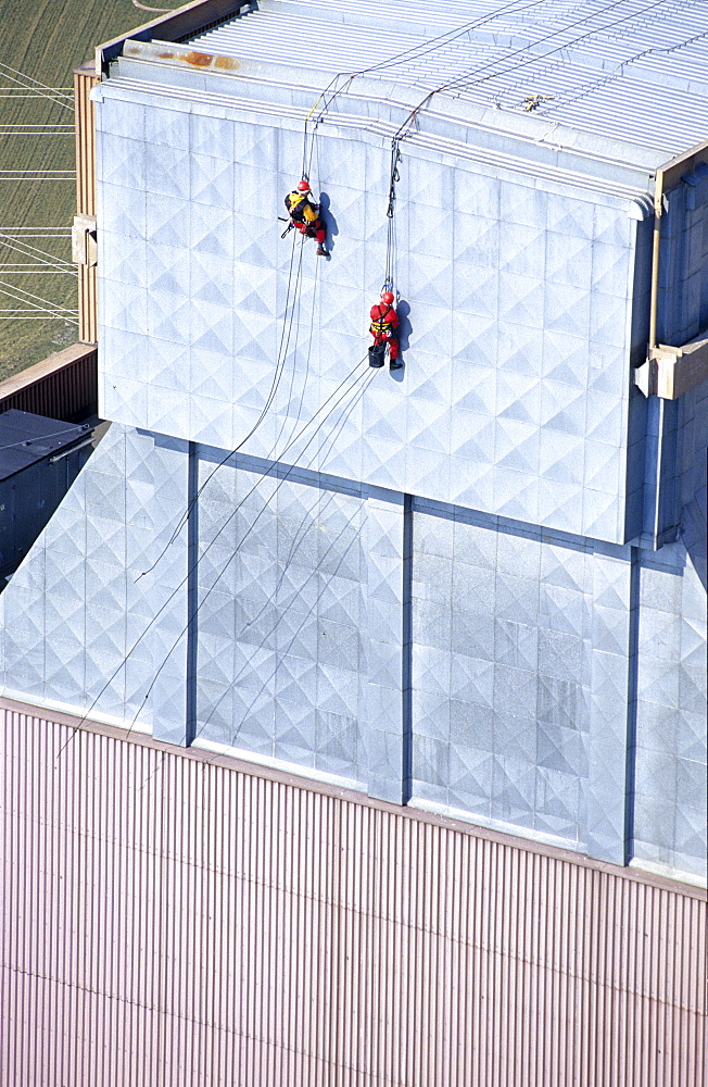 Two workers secured with ropes working on vertical metal surface, renovation works, Duernrohr power plant, Zwentendorf an der Donau, Lower Austria