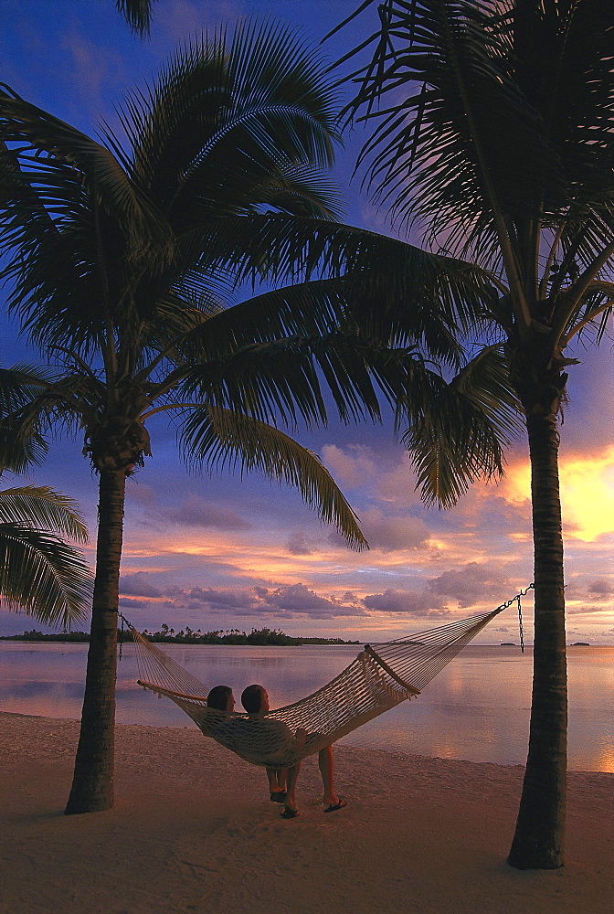 Couple relaxing in a hammock at sunset, Aitutaki Lagoon Resort, Cook Islands, South Pacific