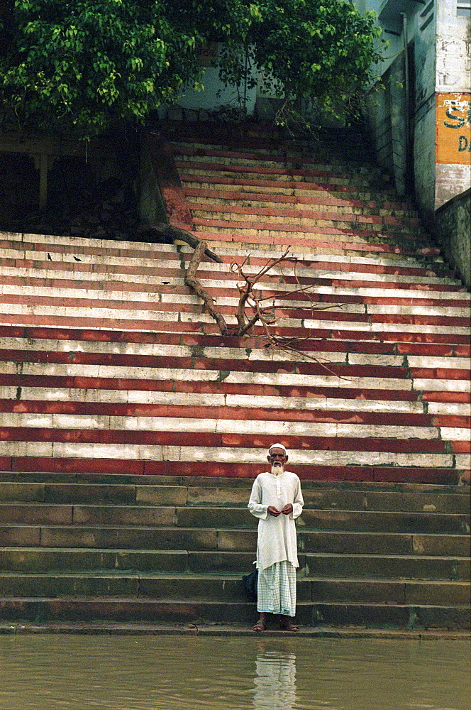 Praying pilgrim standing on stairs at the river Ganges, Ghat, Varanasi, Uttar Pradesh, India