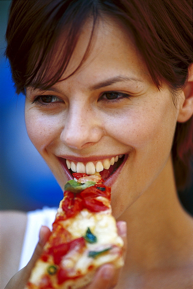 Young woman eating a piece of pizza, Italy, Europe