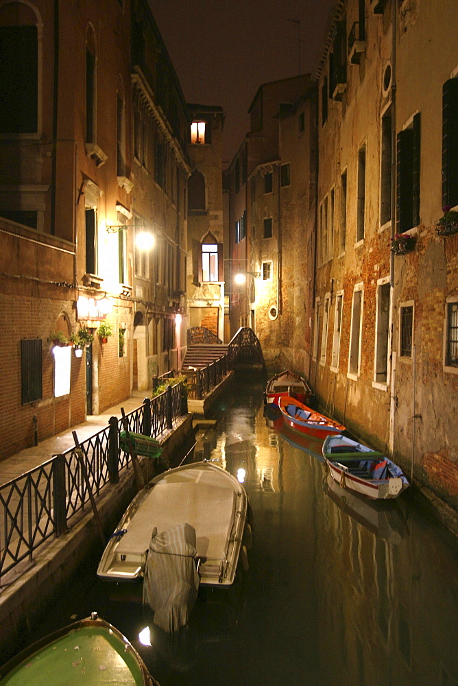 Canal with lights and boats at night in Venice, Italy