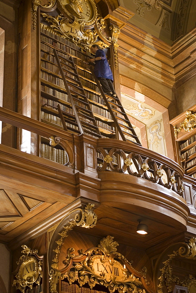 Man sorting books, standing on a ladder, Prunksaal of Nationalbibliothek National Libary, Vienna, Austria