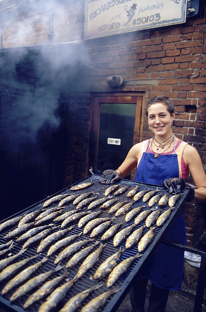 Woman presenting smoked kippers, Orford, Suffolk, England00058424