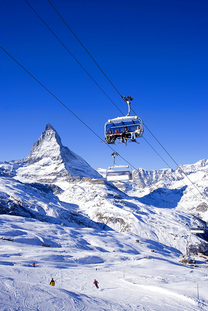 Skiers sitting on a ski lift, Matterhorn (4478 m) in background, Zermatt, Valais, Switzerland