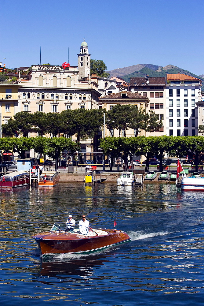 View over Lake Lugano to Luganow with cathedral St. Lorenzo, small motorboat in foreground, Lugano, Ticino, Switzerland