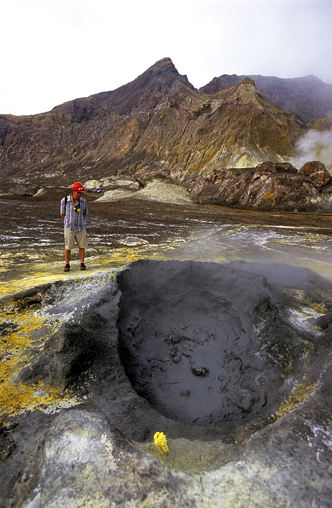 Tourist looking at boiling hot mud on White Island, North Island, New Zealand