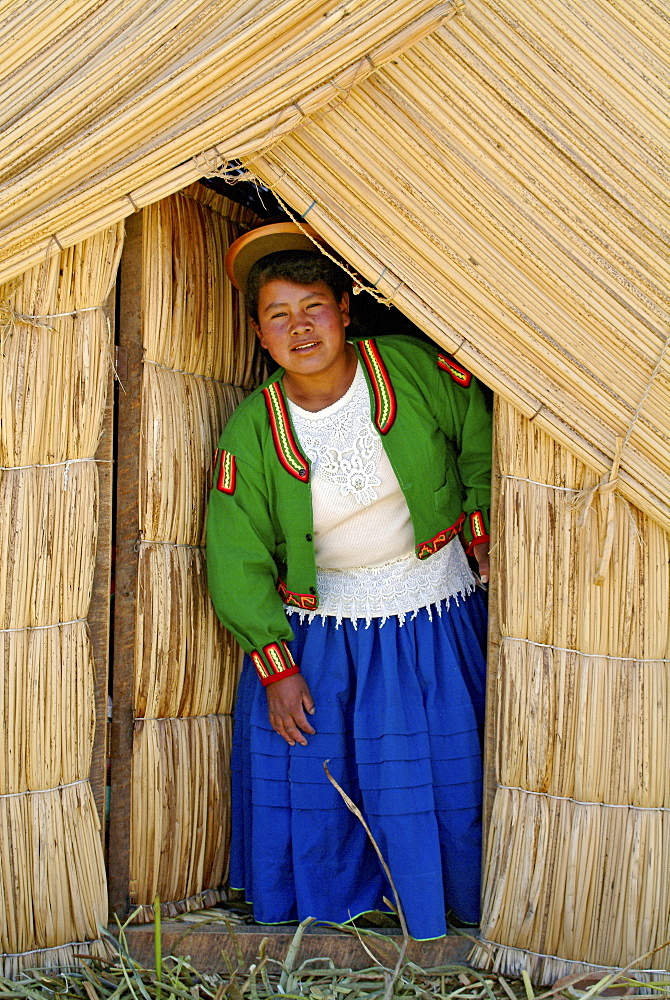 Indigenous woman of the Uros people in front of a reef hut, Lake Titicaca, Peru, South America