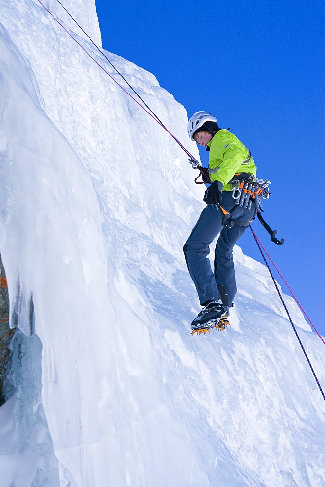 A jung man, an ice climber abseiling on the frozen waterfall, Corn Diavolezza near Pontresina, Grisons, Switzerland, MR