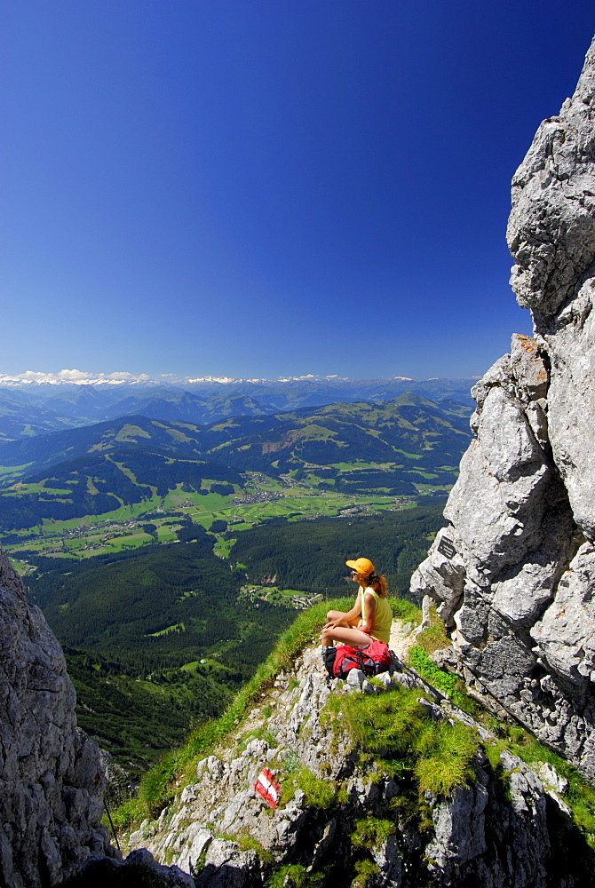 hiker at notch Kleines Toerl with view to the valley of Ellmau and Going, Hohe Tauern in background, Kaiser range, Tyrol, Austria