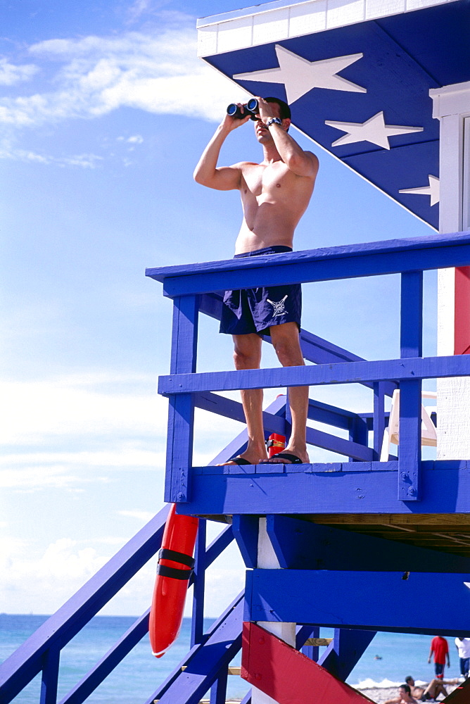 Lifeguard standing in front of a lifeguard hut at the beach, South Beach, Miami, Florida, USA