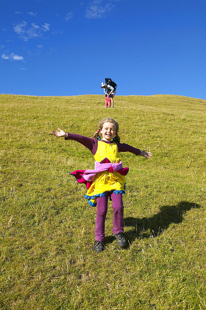 Girl running on farmland, grazing sheep, near Puponga, Golden Bay, northern coast of South Island, New Zealand