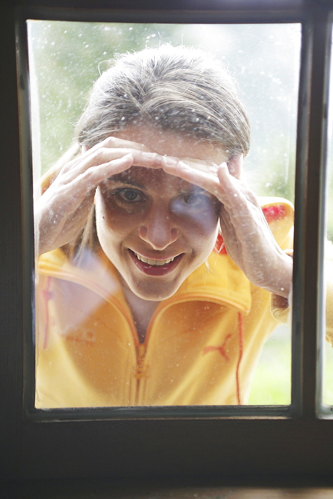 Woman looking through a window into alp lodge, Heiligenblut, Hohe Tauern National Park, Carinthia, Austria