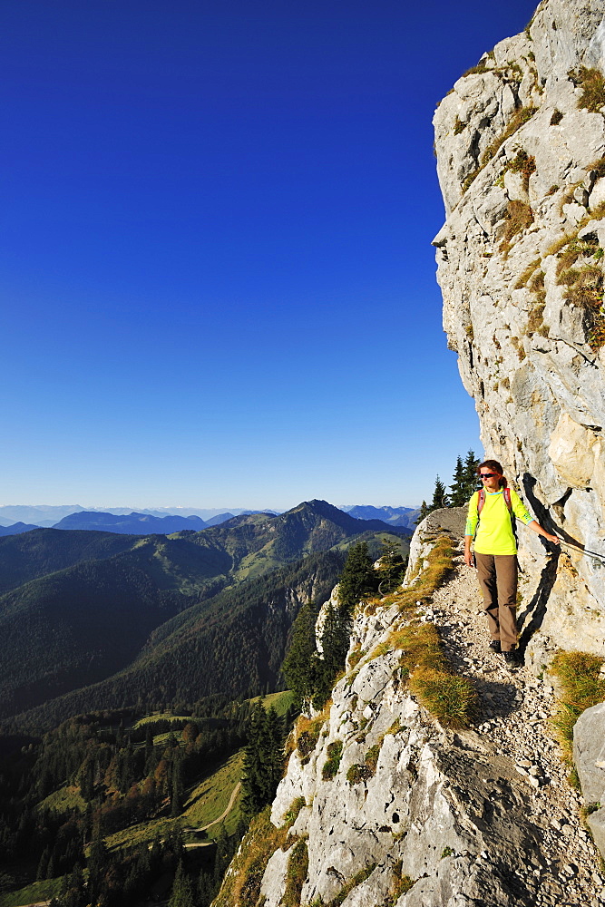 Woman walking on an exposed trail at a rockface, Brunnstein, Bavarian Prealps, Upper Bavaria, Bavaria, Germany