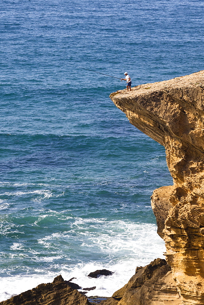 Fisherman on cliff at Monte Clerigo Beach, Atlantic Coast, Algarve, Portugal, Europe