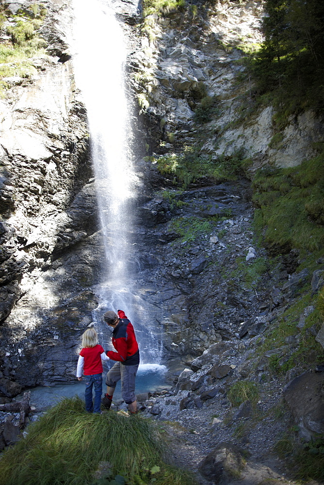 Girl and mountain guide in front of a waterfall, Gossensass, Brenner, South Tyrol, Trentino-Alto Adige/Suedtirol, Italy