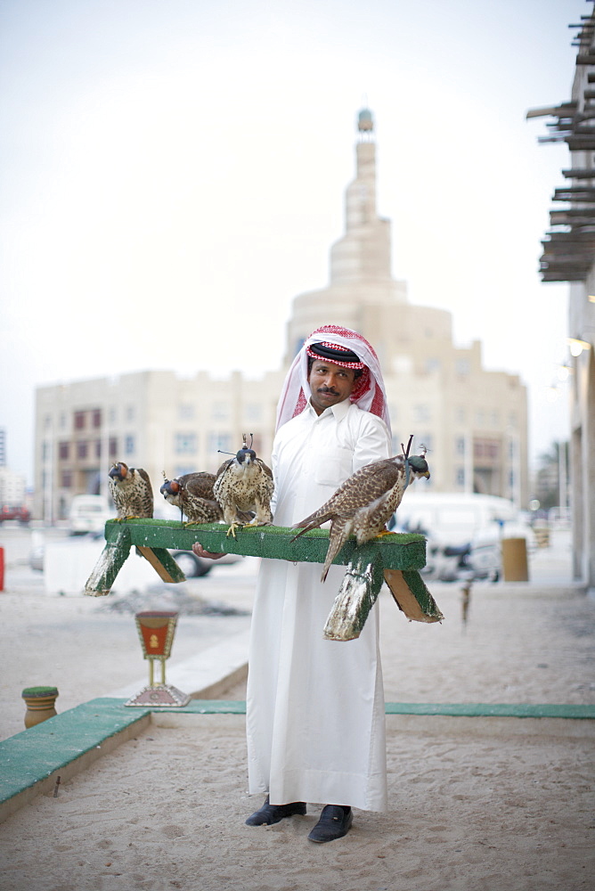 Bird Center salesman with falcons, Islamic Cultural Centre in background, Doha, Qatar