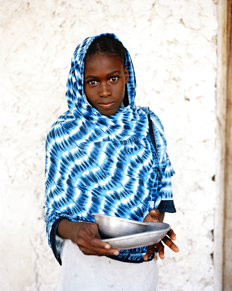 Girl with blue Kanga cloth in front of coral stone house, Jambiani village, Zanzibar, Tanzania, East Africa