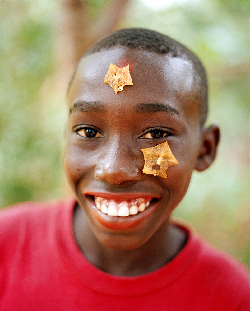 Boy with carambola on his forehead during a Spice Tour on Hakuna Matata Spice Farm, Dole village near Kidichi, north east of Zanzibar Town, Zanzibar, Tanzania, East Africa