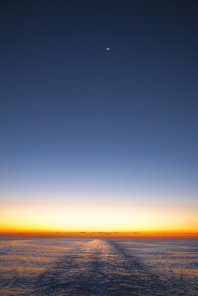 Horizon at dusk with moon, planets and wake from the cruise ship MS Deutschland (Reederei Peter Deilmann), Caribbean Sea, near Cayman Islands