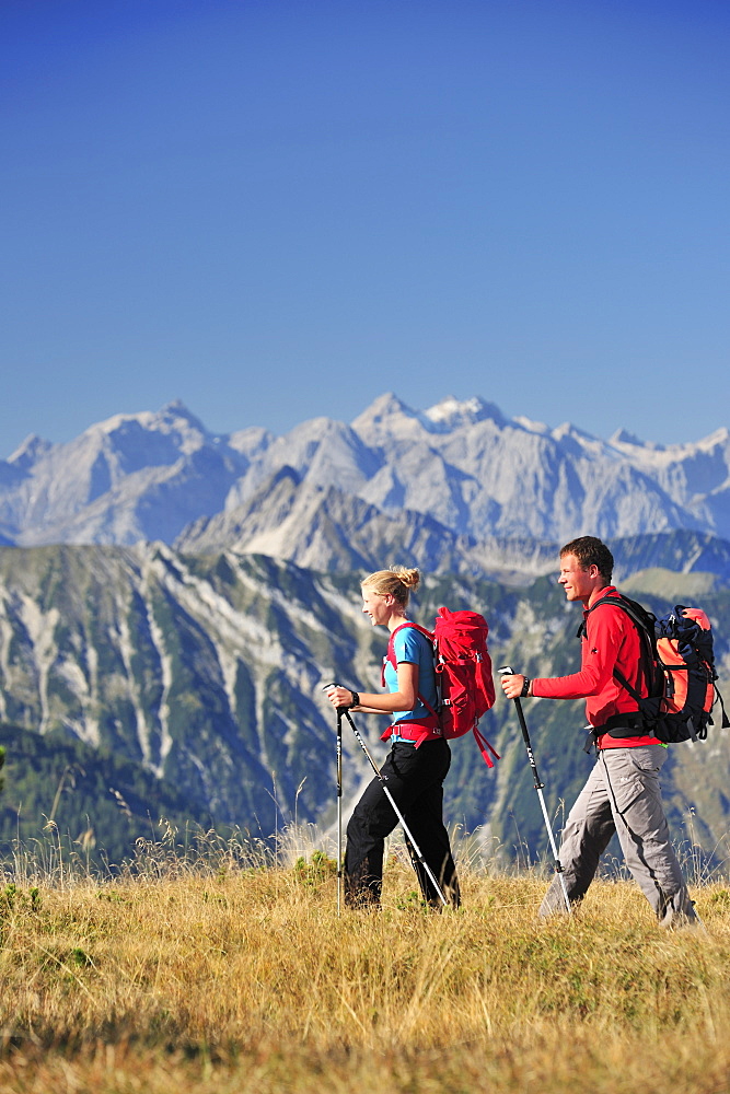 Young woman and young man hiking, Karwendel range in background, Unnutz, Brandenberg Alps, Tyrol, Austria