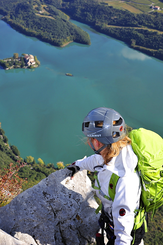 Young woman at fixed rope route Rino Pisetta looking to Lago die Toblino, Sarche, Calavino, Trentino, Trentino-Alto Adige, Suedtirol, Italy