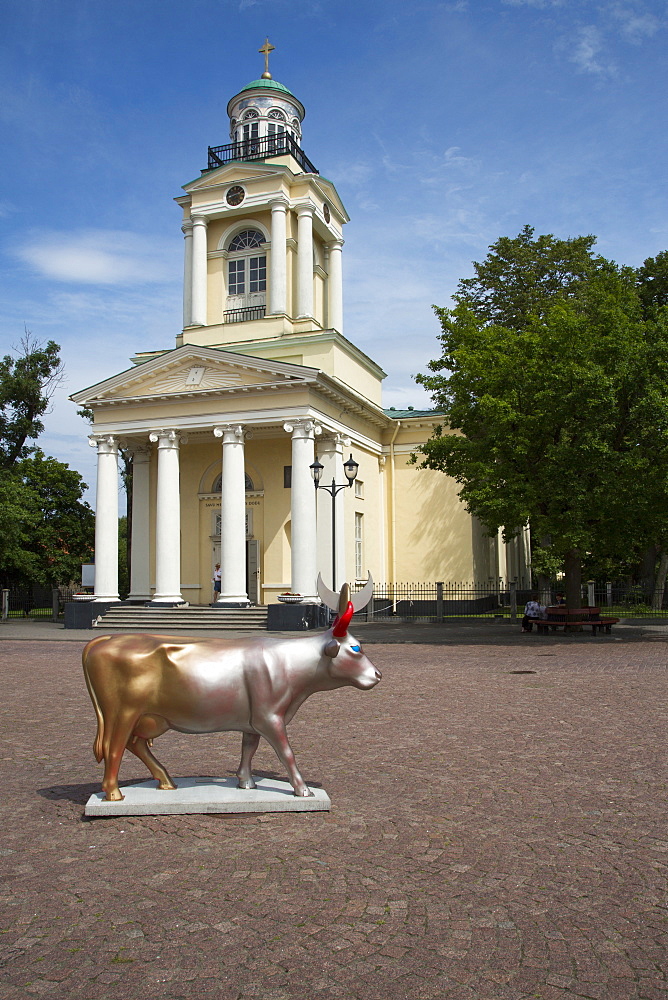 Cow sculpture Cow of Golden Sun and Silver Moon by artist Helena Heinrihsone is part of the Ventspils CowParade art project and situated on the town hall square by St. Nicholas Lutheran church, Ventspils, Latvia, Baltic States, Europe