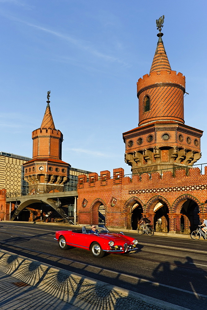 Red cabrio at the Oberbaum Bridge, Oberbaumbruecke over river Spree, architect Otto Stah, Kreuzberg, Berlin