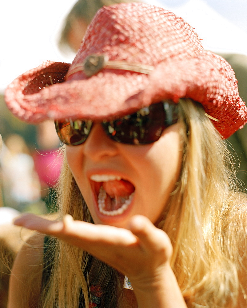 Young woman eating living tree maggot, Hokitika Wildfoods festival, Hokitika, South Island, New Zealand